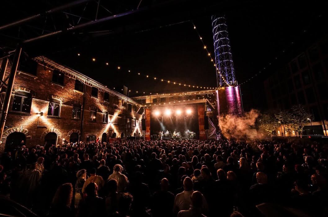 A night-time concert filling the historic courtyard with a view towards the stage