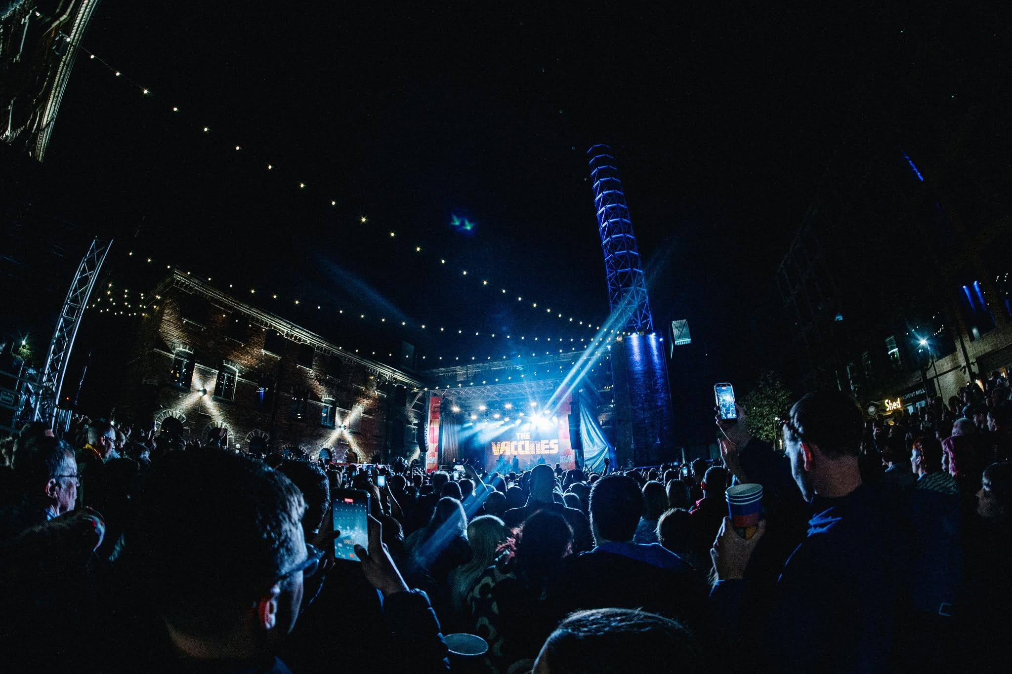 A capacity crowd watching The Vaccines beneath the courtyard lights